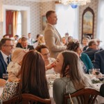 Isot pöydät kartanon juhlasalissa luovat lämminhenkistä tunnelmaa juhliin. Juhlavieraita kartanon salissa.