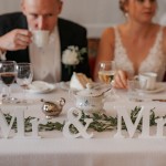 Vietä tunnelmallinen juhlapäivä Tiittalan kartanolla. Hääpari pöydän ääressä.